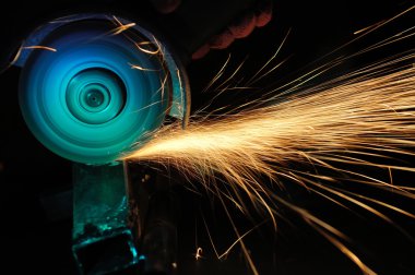 Öğütücüyle metal kesen bir işçi