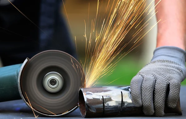 Öğütücüyle metal kesen bir işçi