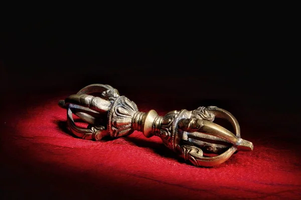 Meditasyon yapan Tibetli vajra, siyah bir arkaplanda kırmızı bir kumaşın üzerinde yatıyor.