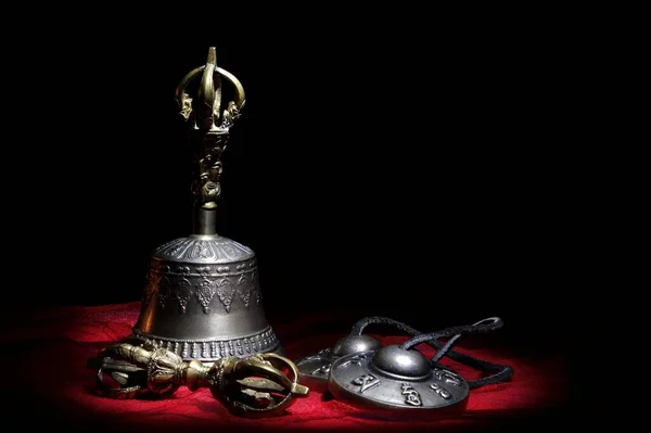 Siyah bir arka planda kırmızı bir kumaş üzerinde uzanan vajina ve Tingsha ve ghanta Tibet meditasyon çanları