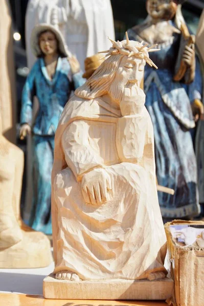 Düşünceli İsa 'nın ahşap figürü diğer halk heykellerinin arka planında bir tezgahta duruyor.