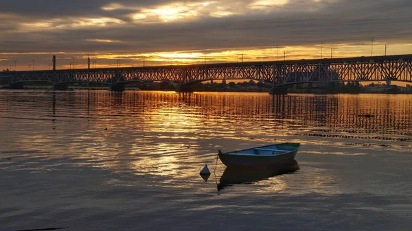 Plock 'taki Vistula Nehri üzerinde gün batımına karşı bir tekne ve bir köprü..