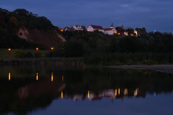Suyu aydınlatan parlayan fenerler ve Pock 'taki tepede bulunan tarihi binalar..