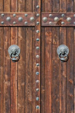 Antik ahşap kapıdaki paslı metal tokmağın yakın çekimi.
