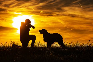 Gün batımında bir çocuk ve bir köpeğin silueti, fotoğrafçı çok yakın bir portre çeker.