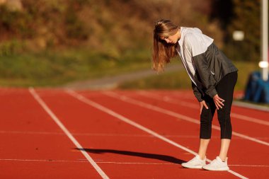 young woman in sportswear running on the track