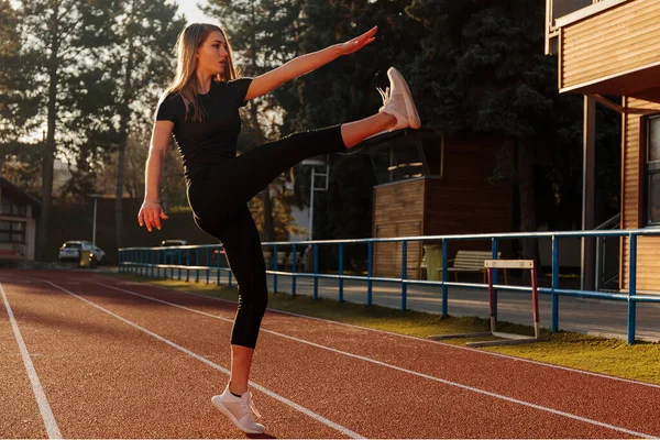 Stadyumda esneme hareketleri yapan genç bir kadın.