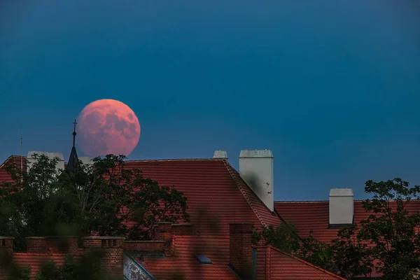 super full moon just rising above the rooftops of Prague