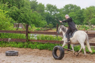 Kadın at sırtında yayla ateş ediyor.