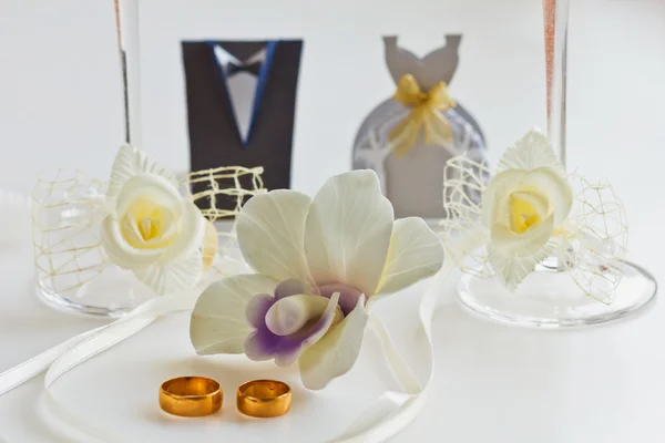 Due fedi nuziali su bianco con orchidee per sfondo — Foto Stock