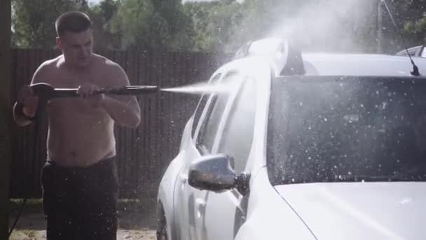 The concept of car service, personal car, car wash. The process of washing a personal car at a self-service car wash. Man washing his white car with a hose — Stock Video