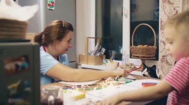 Yeni yıl arifesinde, anaokulu çağında bir anne ve oğlu Noel Baba şeklinde çıkartmalar çizip yapıştırdılar, sonra da sevimli siyah bir kediyle oynamaya başladılar..