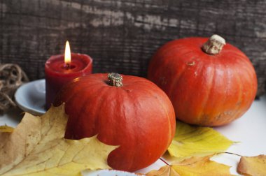 Sarı sonbahar yapraklı balkabakları ve ahşap arka planda bir mum.
