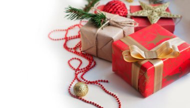 Kırmızı, altın ve bej renkli kutular kurdeleli, boncuklu, yıldızlı, ladin dallı. Beyaz bir arka planda yılbaşı süsleri olan Noel hediyeleri. Metin için yer