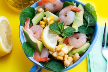 Karidesli salata, avokado, mısır ve limon, sarı arka planda zeytinyağı. Üst görünüm