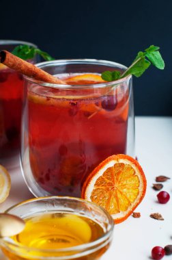 Beyaz arka planda kızılcık, portakal, limon, tarçın, bal ve nane ile çay. Meyve çayı ve baharatlı bardak.