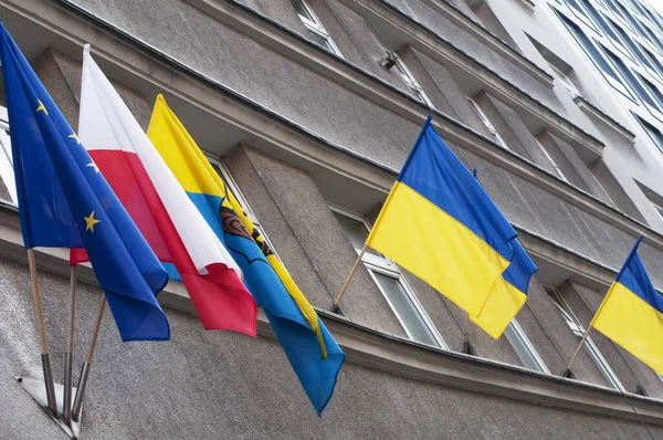 Flags of Ukraine, Poland, EU, Katowice on the background of gray houses. Solidarity of Poland and EU countries with Ukraine