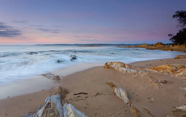 Las olas golpean suavemente la tranquila playa al amanecer — Foto de Stock