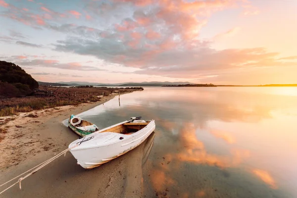 Altes Boot mit Sonnenaufgangsreflexen am sandigen Ufer festgemacht — Stockfoto