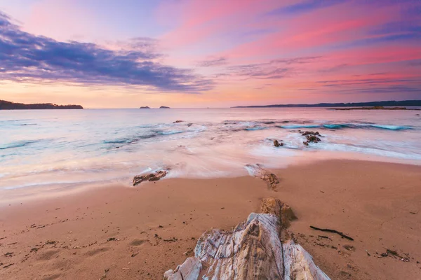 Pastel beach sunrise as gentle waves wash shore — Stock fotografie