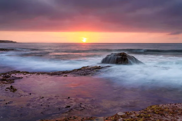 Güneş gökyüzünü kırmızı ve sarı ile aydınlatırken Tekne Limanı 'nda fırtına bulutları beliriyor.