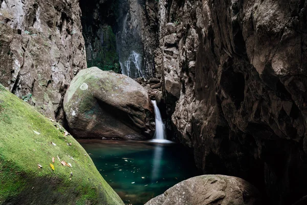 高くそびえる岩があるかなり秘密の岩のプールに小さな滝 ストック写真