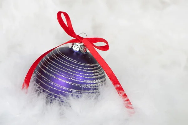 Purple christmas bauble on feathers — Stock Photo, Image