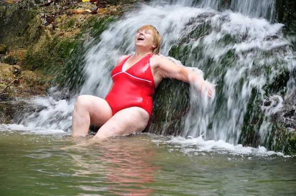 Adult woman in red swimsuit enjoying a waterfall — Stock Photo, Image