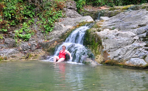 Adult woman in red swimsuit near a waterfall — Stock Photo, Image