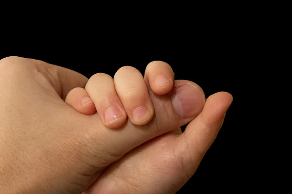 The hand of the child holds a finger of the father on a black ba — Stock Photo, Image