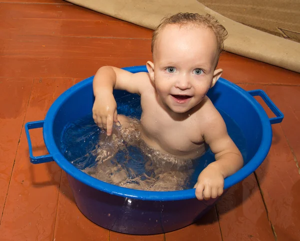 O menino é banhado em uma banheira azul — Fotografia de Stock