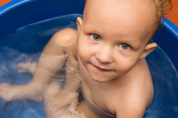 Der kleine Junge wird in einer blauen Wanne gebadet — Stockfoto