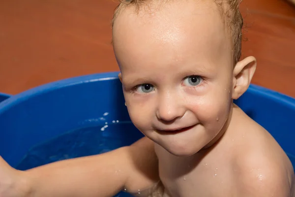 Den lille dreng er badet i et blåt badekar - Stock-foto