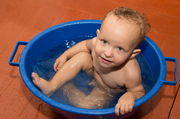 O menino é banhado em uma banheira azul — Fotografia de Stock