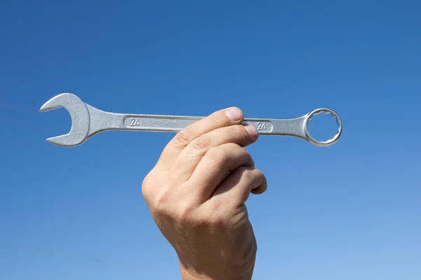 Hand with a wrench on a background of the sparkling sky. — Stock Photo, Image