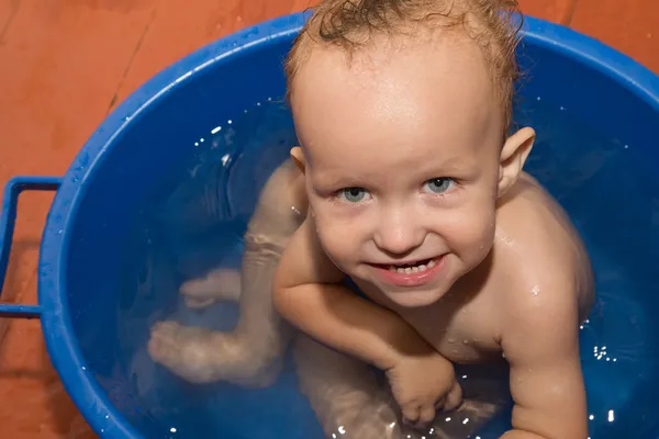 O menino é banhado em uma banheira azul — Fotografia de Stock