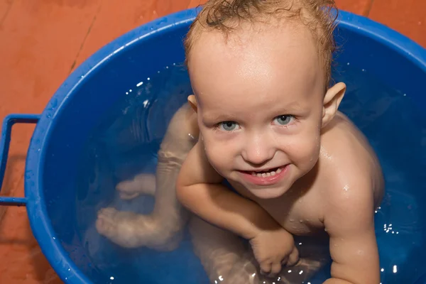The little boy is bathed in a blue tub Stock Image
