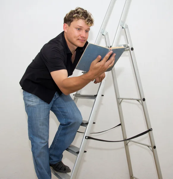 Um homem com uma escada e um livro — Fotografia de Stock