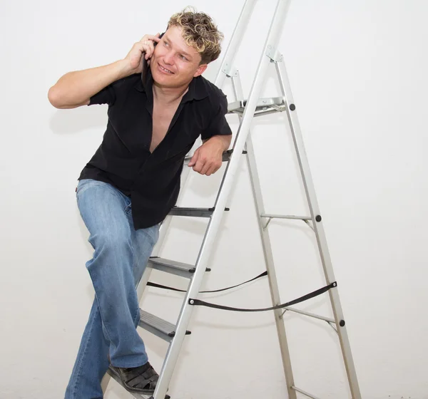 A man with a cell on a stepladder on a white background — Stock Photo, Image