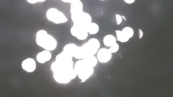 Mooie bokeh van de stralen van de zon op het water — Stockvideo