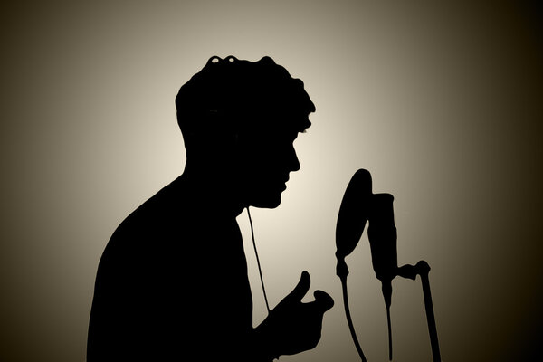 man in headphones singing into a microphone on a white backgroun