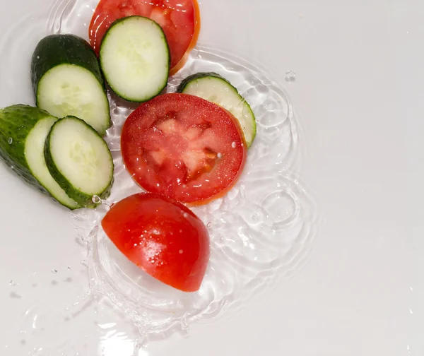 Gurke und Tomate in Wasser auf weißem Hintergrund — Stockfoto