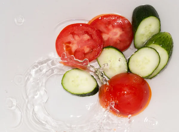 Pepino y tomate en agua sobre fondo blanco — Foto de Stock