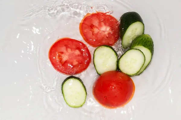 Gurke und Tomate in Wasser auf weißem Hintergrund — Stockfoto