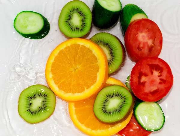 Fruits et légumes frais dans l'eau sur fond blanc — Photo