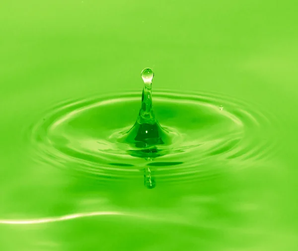 Uma gota de água cai na água verde — Fotografia de Stock