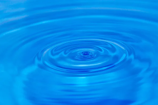 Een druppel water vallen in blauwe water — Stockfoto