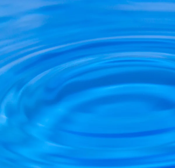 Una goccia d'acqua che cade in acqua blu — Foto Stock