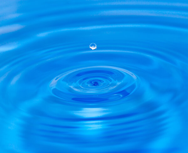 A drop of water falling in blue water