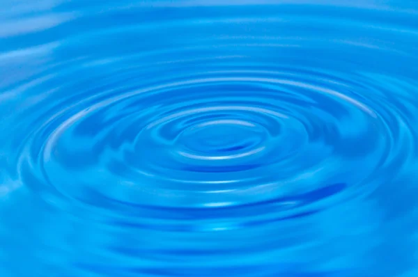Una goccia d'acqua che cade in acqua blu — Foto Stock